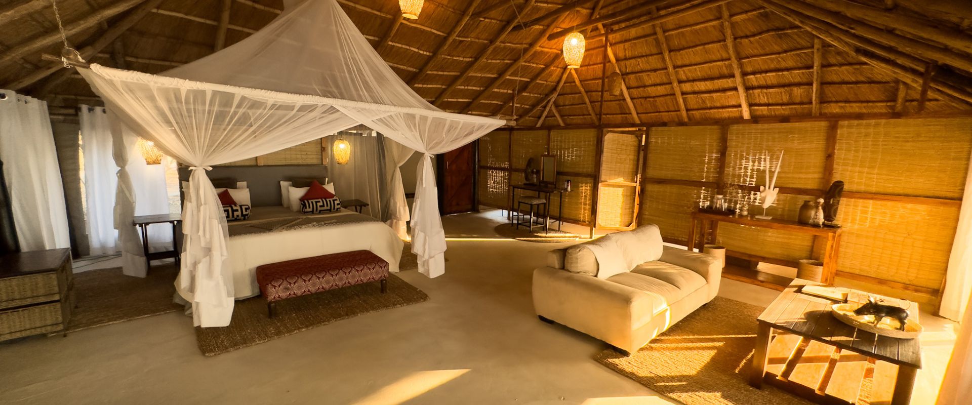 Guest bedroom and sitting area beneath a thatched roof at Vundu Camp